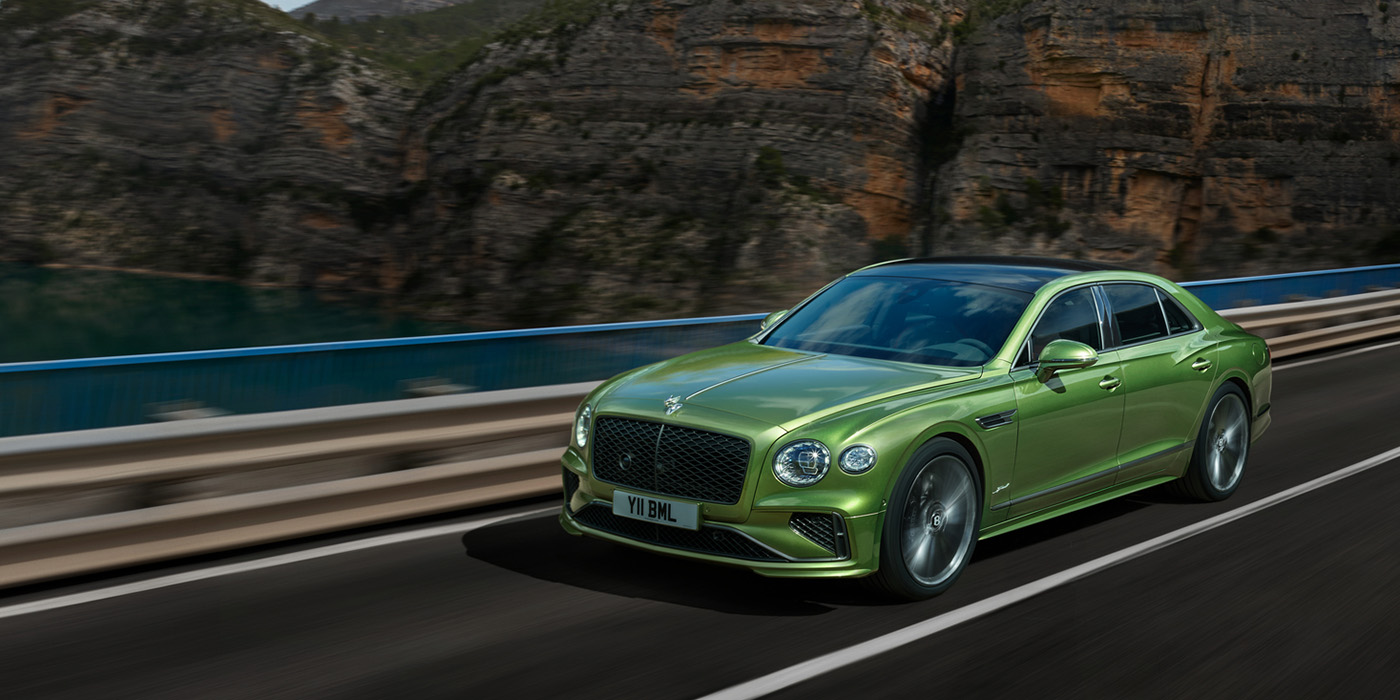 Bentley Cyprus Bentley New Flying Spur Speed v8 hybrid sedan driving dynamically on a mountain road in Tourmaline Green paint