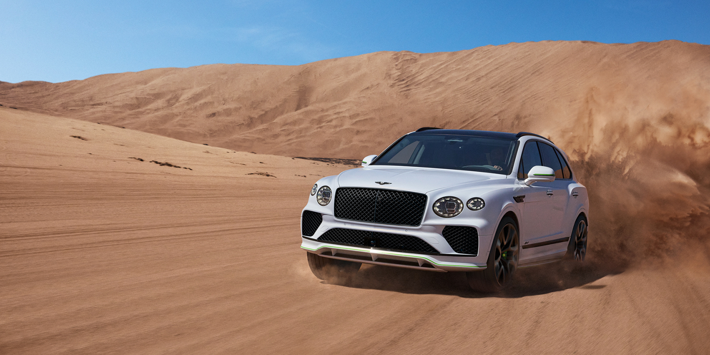 Bentley Cyprus Bentley Bentayga Speed SUV front three quarter in Snow Quarts Pearlescent by Mulliner white paint driving dynamically through the desert
