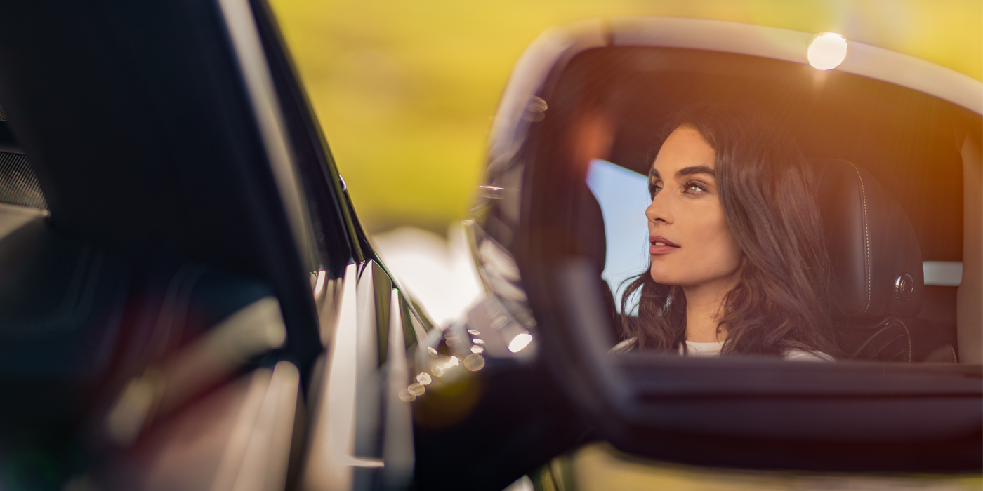 Bentley Cyprus profile of dark haired woman's face in mirror of Bentley car in sunlight