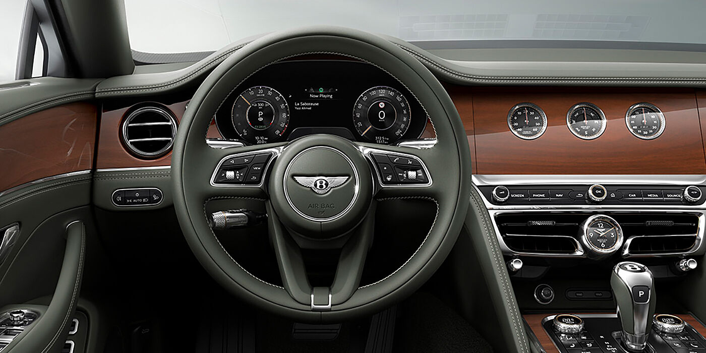 Bentley Cyprus New Bentley Flying Spur sedan front cabin in Cumbrian Green hide and Crown Cut walnut veneer showing steering wheel and Rotating Display with three clocks on face