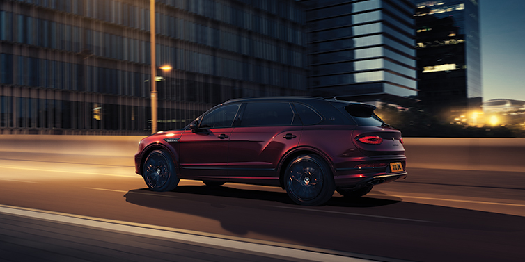 Bentley Cyprus Bentley Bentayga Extended Wheelbase Mulliner SUV in Cricket Ball red paint driving dynamically in city at night
